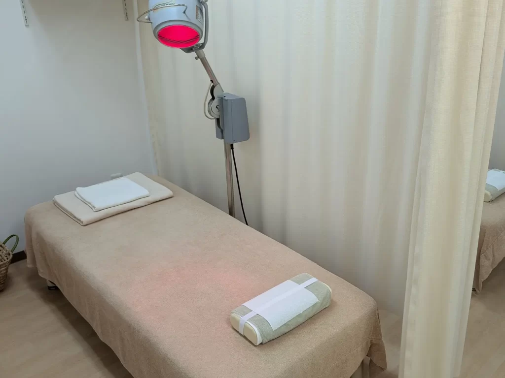 清潔でリラックスできるひごころ治療院の施術室と、身体を芯から温める赤外線治療器