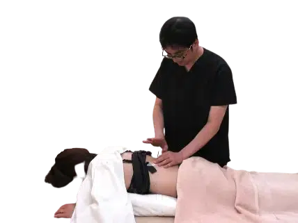 武蔵小杉の鍼灸院ひごころ治療院で、院長が患者様の背中を丁寧に触診・施術している様子